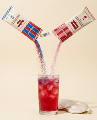 Powder pouring from a torn stick pack into a glass